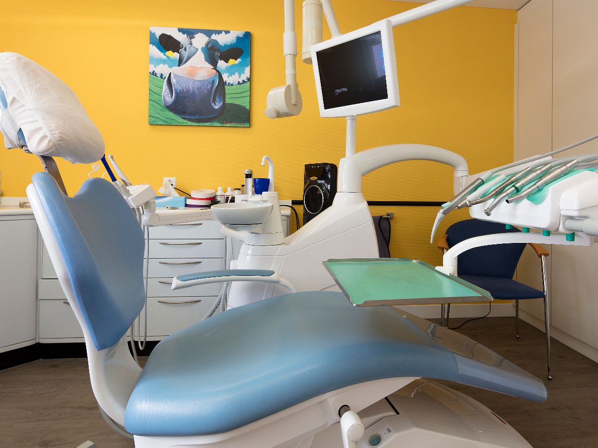 Behandlungszimmer mit blauem Behandlungsstuhl und Tageslicht